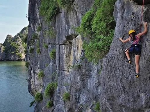 A roped climber on a limestone wall overlooking the sea and islands