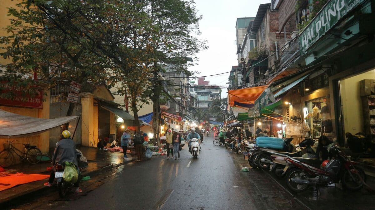 Narrow Old Quarter street in Hanoi lined with motorbikes and shopfronts