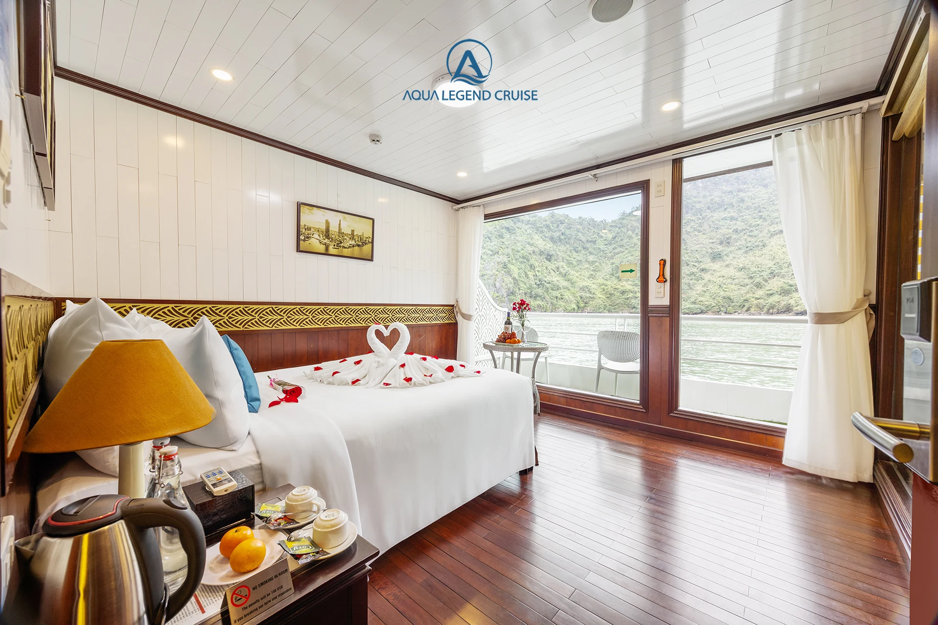 Senior Suite Balcony cabin with a double bed, towel swans and a glass door to the balcony on Aqua Legend Cruise
