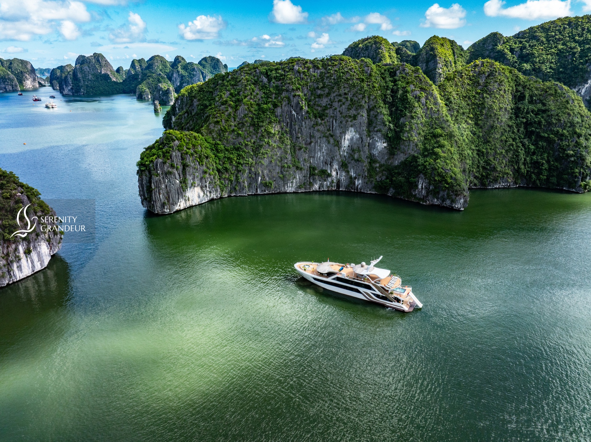 Cruise boat anchored in an emerald lagoon surrounded by karst cliffs